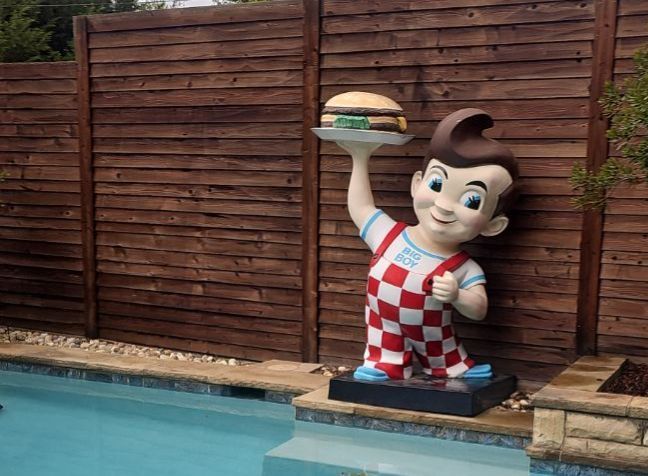Vintage Big Boy restaurant statue beside a swimming pool at a Richardson roofing project.
