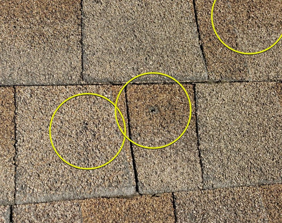 Circled areas on aging asphalt shingles during a roof inspection in Lakewood Dallas 75214