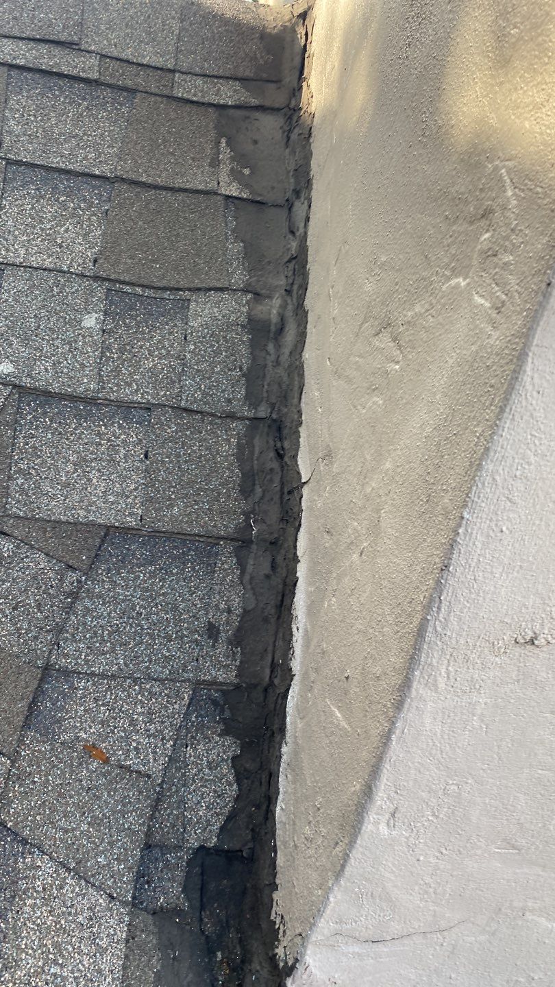 Chimney flashing repair in Dallas 75206 showing heavy black roofing cement around the chimney before repair