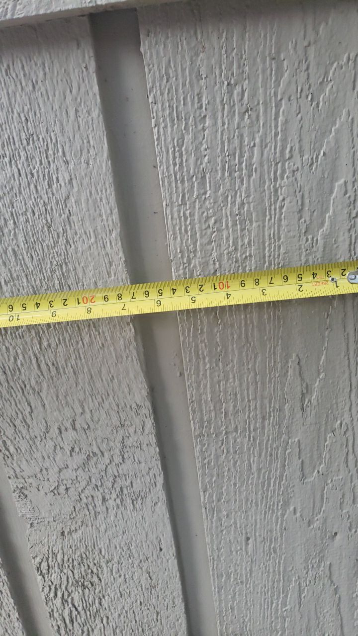 Measuring the existing 1x8 cedar lap-and-gap siding during a Lake Highlands insurance restoration.