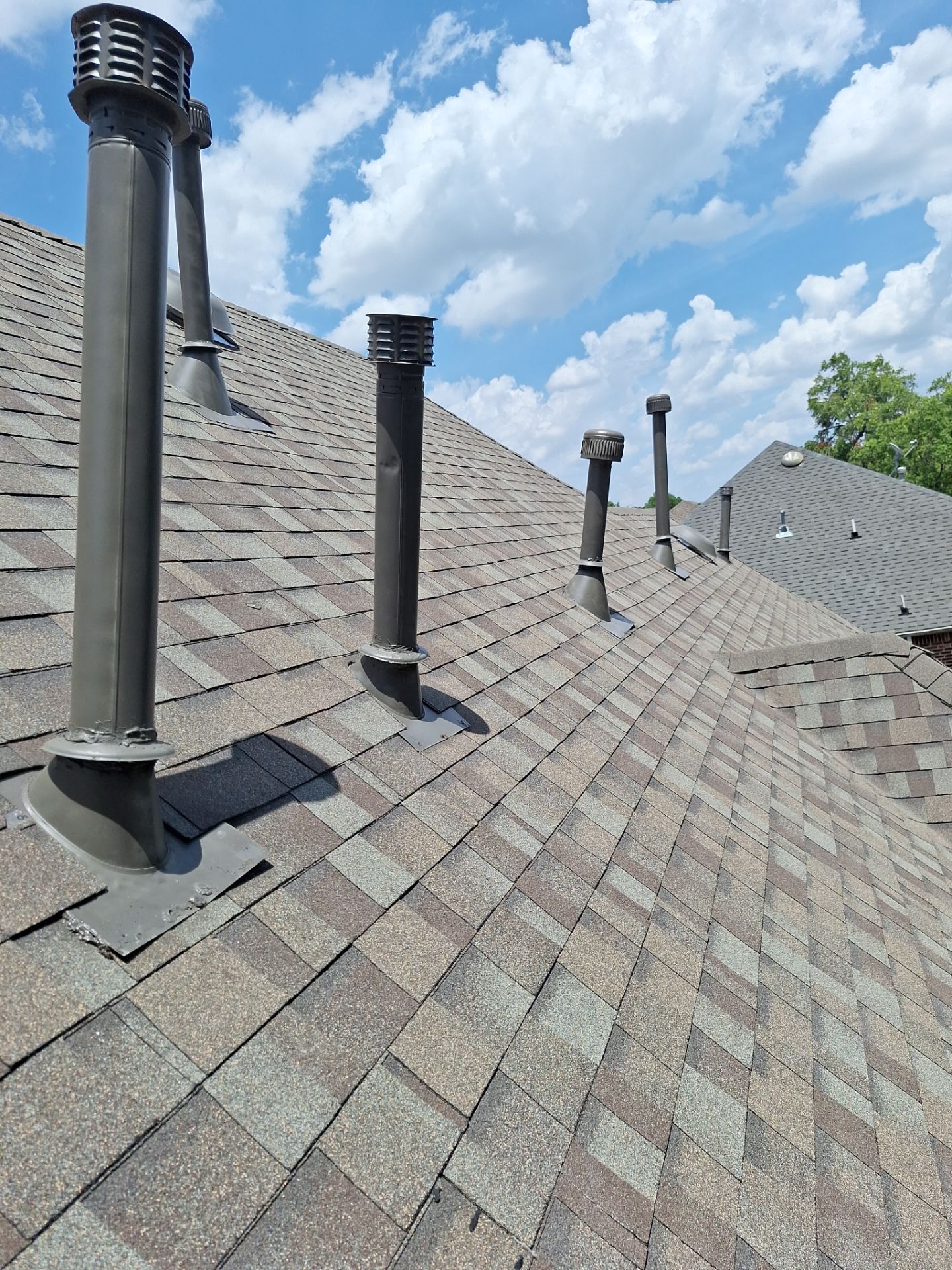 Multiple custom-fitted mechanical vent pipes on a steep Preston Hollow roof in Dallas.