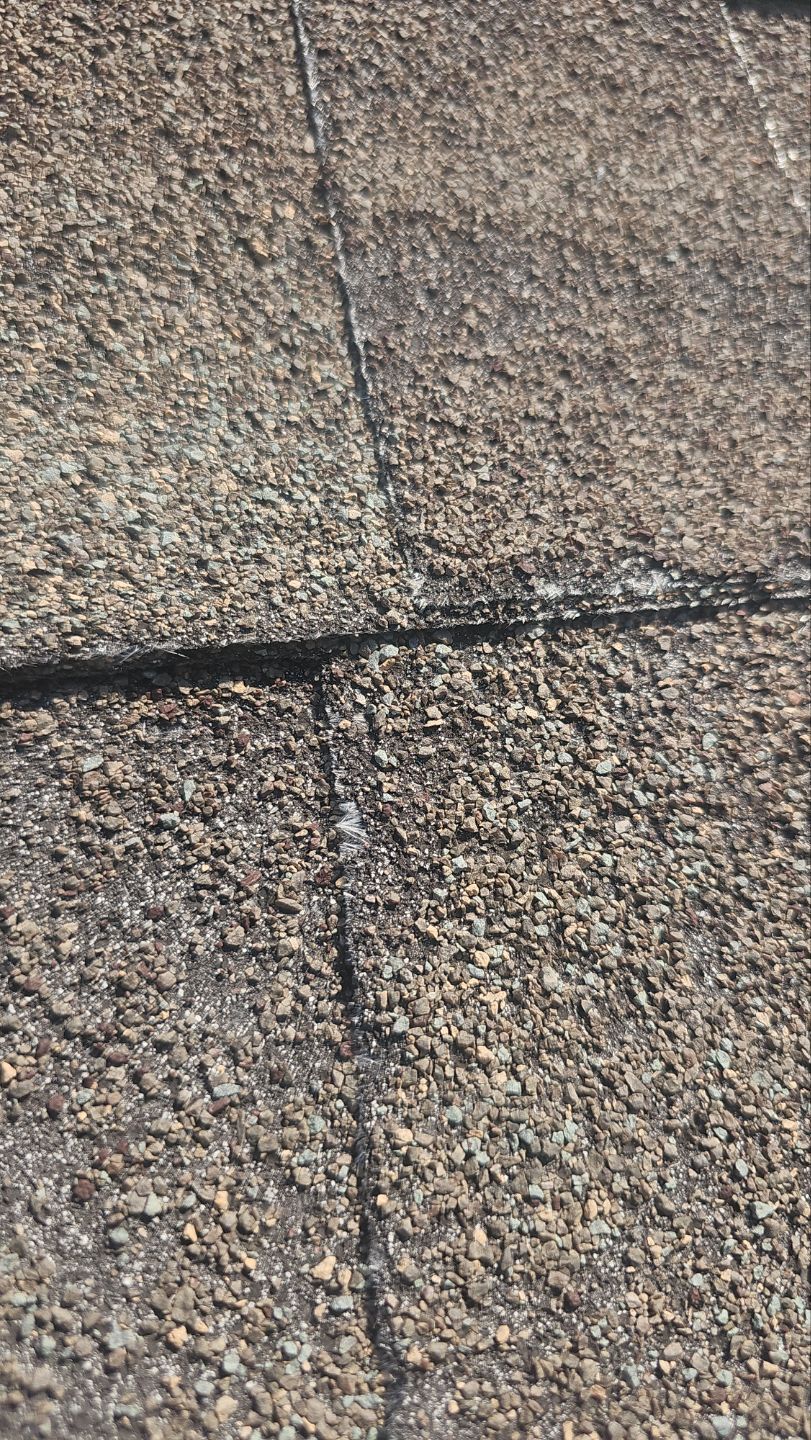 Close-up of deteriorated asphalt shingles with granule loss and exposed fiberglass matting before an East Dallas roof replacement.